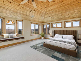 This stunning bedroom boasts a unique architectural design with a vaulted, wood-paneled ceiling that adds warmth and character.