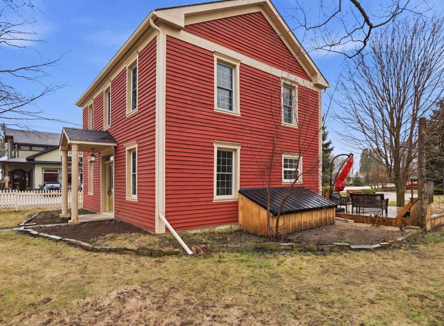 This charming two-story home boasts a vibrant red exterior, creating a striking curb appeal.