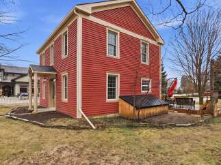 This charming two-story home boasts a vibrant red exterior, creating a striking curb appeal.