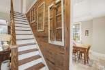 This charming home features a beautifully crafted staircase with wooden steps and white risers, complemented by a rustic wooden accent wall.