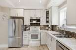 This stunning kitchen boasts modern white cabinetry, stainless steel appliances, and a beautiful backsplash.
