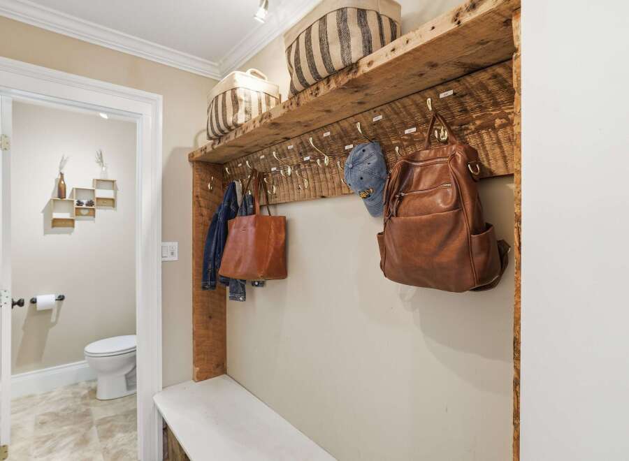 This inviting entryway features a rustic wooden shelf with hooks, perfect for hanging coats, bags, and hats.