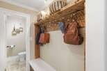 This inviting entryway features a rustic wooden shelf with hooks, perfect for hanging coats, bags, and hats.