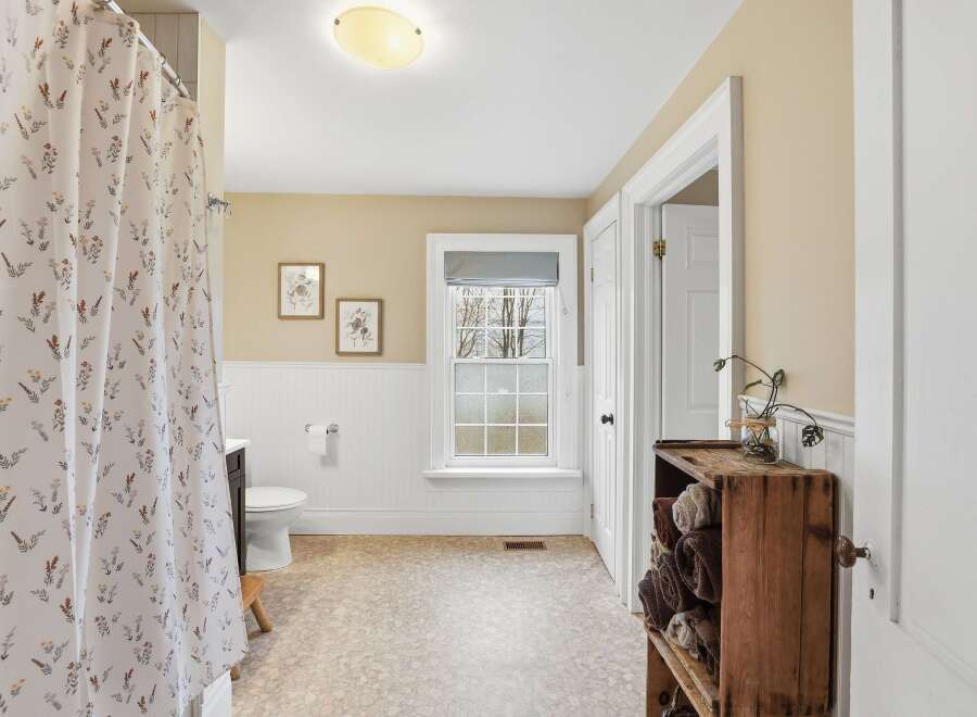 Step into this charming bathroom, featuring a delightful floral shower curtain and a cozy, inviting atmosphere.