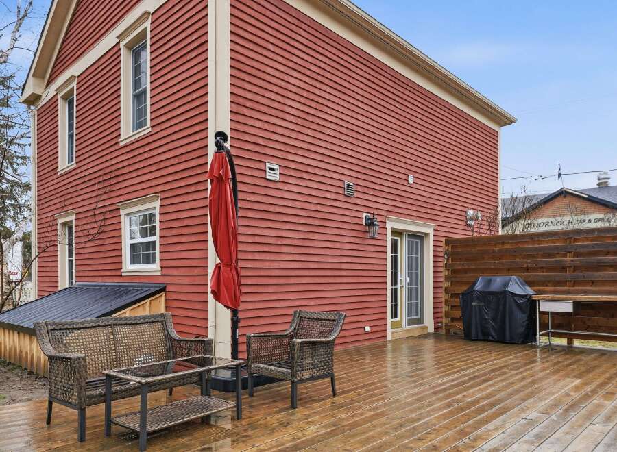 This charming property boasts a stunning red exterior and a spacious wooden deck, perfect for outdoor entertaining.