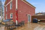 This charming property boasts a stunning red exterior and a spacious wooden deck, perfect for outdoor entertaining.