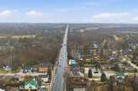 An aerial view showcases a charming town with a long road cutting through the center, lined with houses and businesses.
