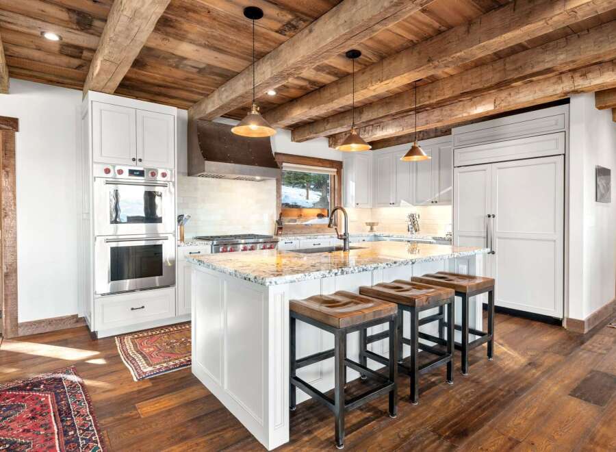 This stunning kitchen boasts a rustic charm with its exposed wooden beams and elegant white cabinetry.