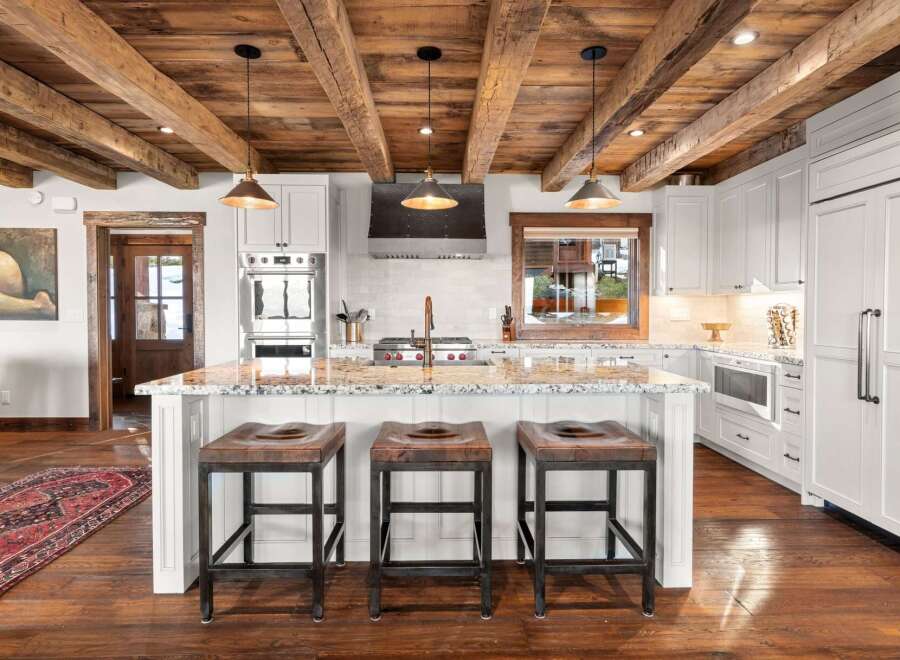 This stunning kitchen boasts a rustic charm with its exposed wooden beams and elegant pendant lighting.