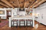 This stunning kitchen boasts a rustic charm with its exposed wooden beams and elegant pendant lighting.