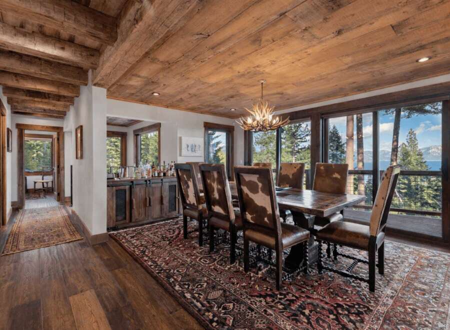 Step into luxury with this stunning dining room, featuring a rustic wooden ceiling and elegant antler chandelier.