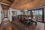 Step into luxury with this stunning dining room, featuring a rustic wooden ceiling and elegant antler chandelier.