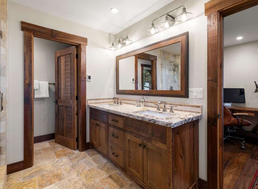 This stunning bathroom boasts a rustic charm with its wooden cabinetry and trim, creating a warm and inviting atmosphere.