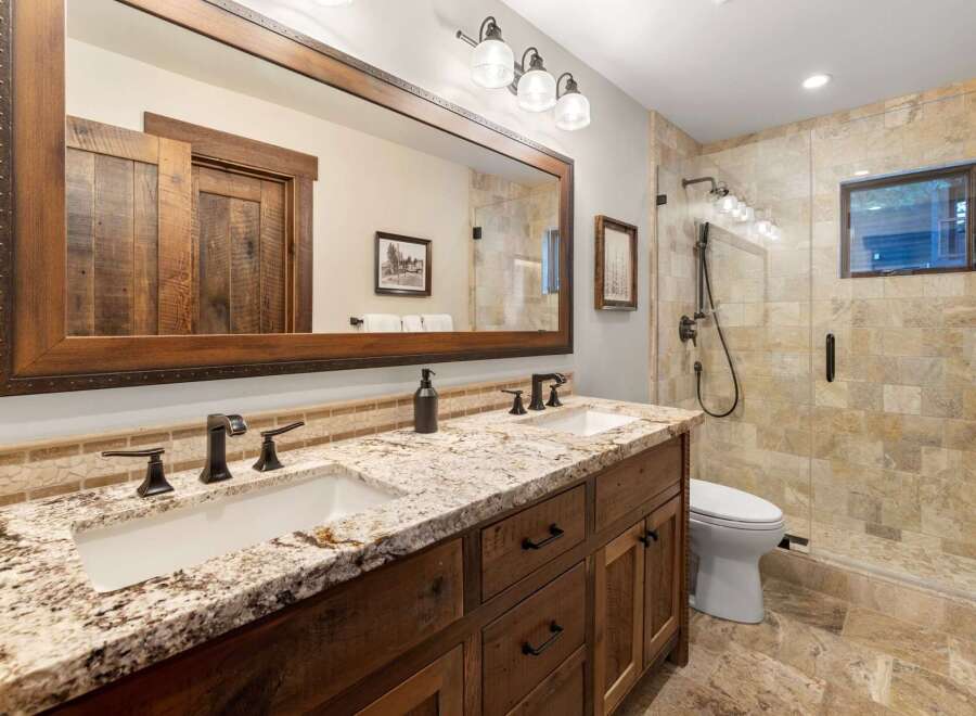 This stunning bathroom features a rustic design with a double vanity and a large mirror.