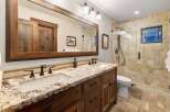 This stunning bathroom features a rustic design with a double vanity and a large mirror.