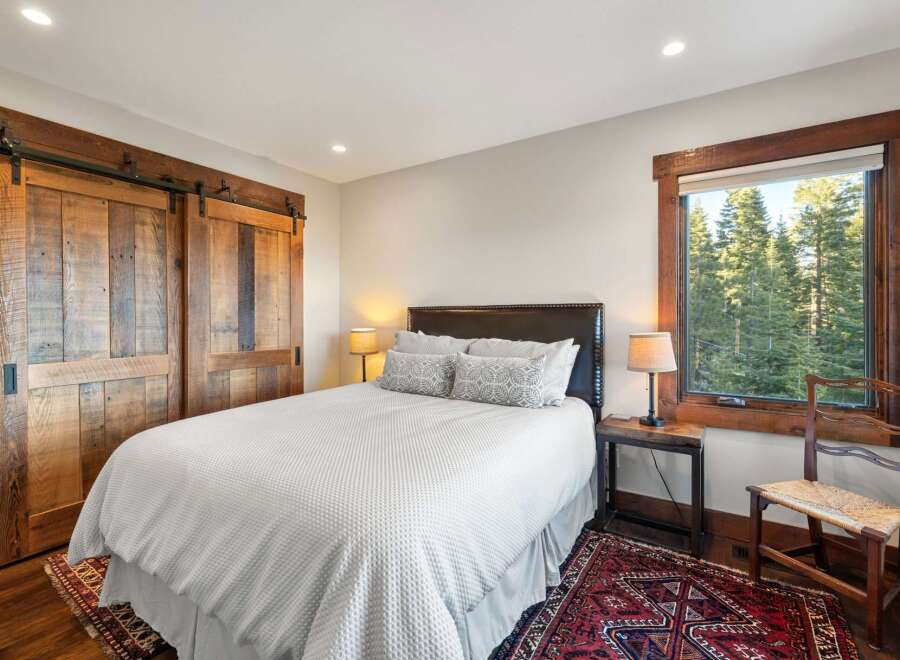 This stunning bedroom boasts rustic charm with its wooden barn doors and window trim.