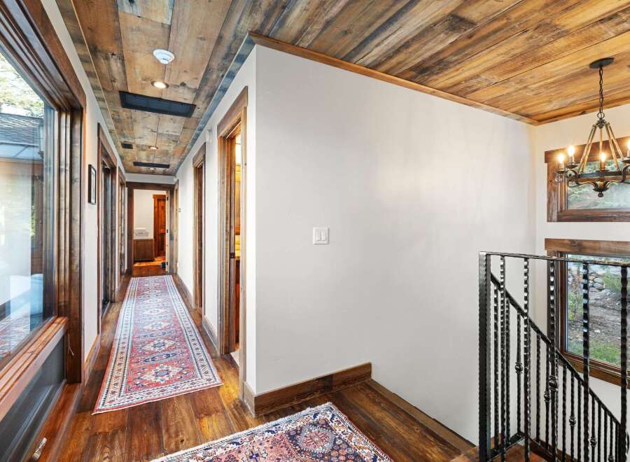 Step into luxury with this stunning hallway featuring a rustic wooden ceiling and elegant hardwood floors.