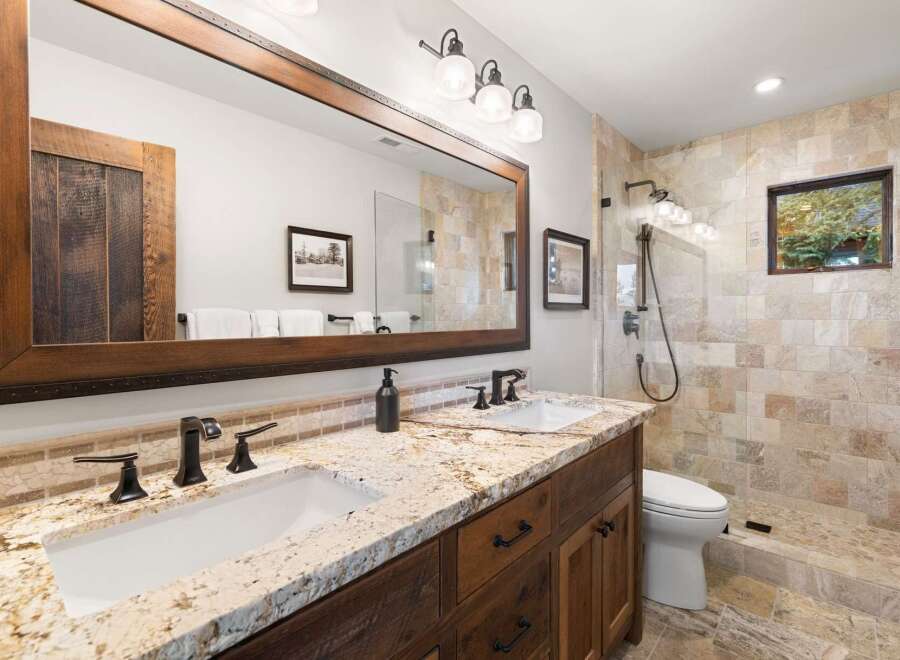 This stunning bathroom boasts a rustic design with a large wooden-framed mirror and a granite countertop.