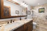 This stunning bathroom boasts a rustic design with a large wooden-framed mirror and a granite countertop.