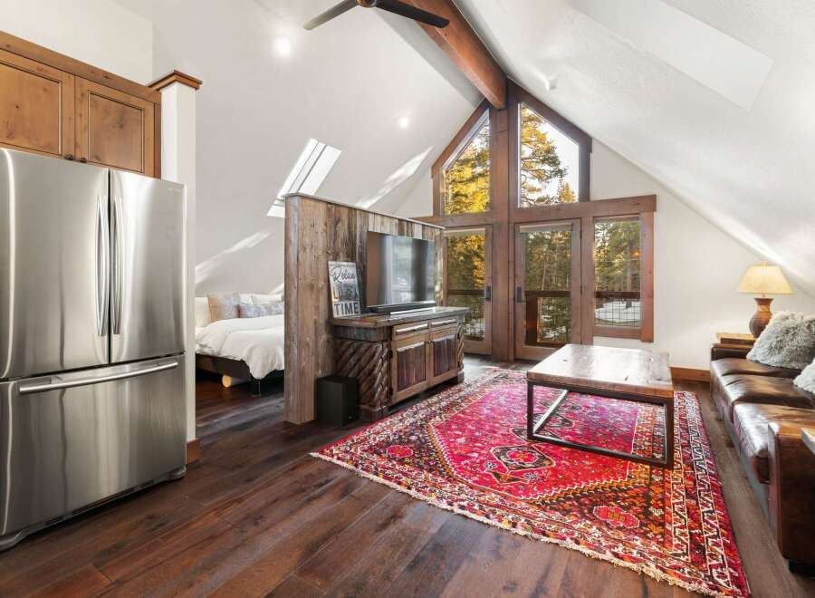This stunning property boasts a cozy living space with a rustic charm, featuring a beautiful red rug and a stylish coffee table.