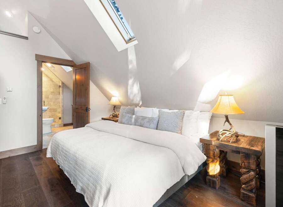 This stunning bedroom boasts a unique architectural design with a sloped ceiling and a skylight that floods the space with natural light.