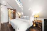 This stunning bedroom boasts a unique architectural design with a sloped ceiling and a skylight that floods the space with natural light.
