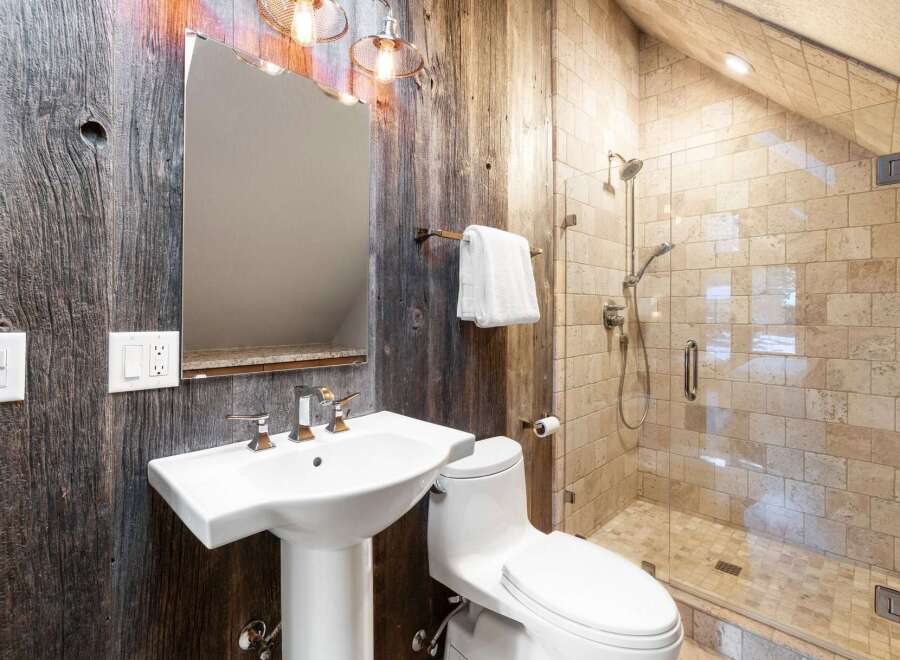 This stunning bathroom boasts a rustic charm with its reclaimed wood walls and modern fixtures.