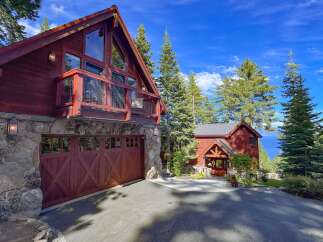 Experience luxury mountain living in this stunning timber-frame home, featuring a spacious garage and a charming covered entryway.