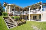This charming home features a multi-level backyard with wooden stairs leading to a lush green lawn.