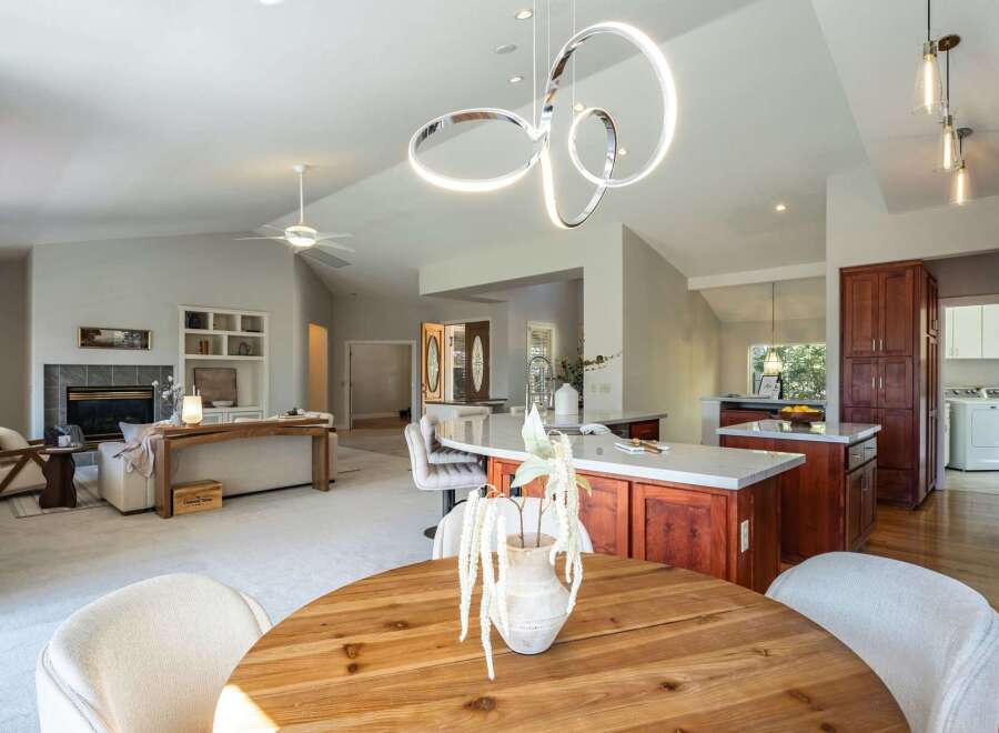 Experience open-concept living in this stunning home, featuring a spacious kitchen with a large island and rich wood cabinetry, seamlessly flowing into a bright living area with a cozy fireplace.