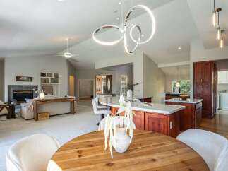 Experience open-concept living in this stunning home, featuring a spacious kitchen with a large island and rich wood cabinetry, seamlessly flowing into a bright living area with a cozy fireplace.