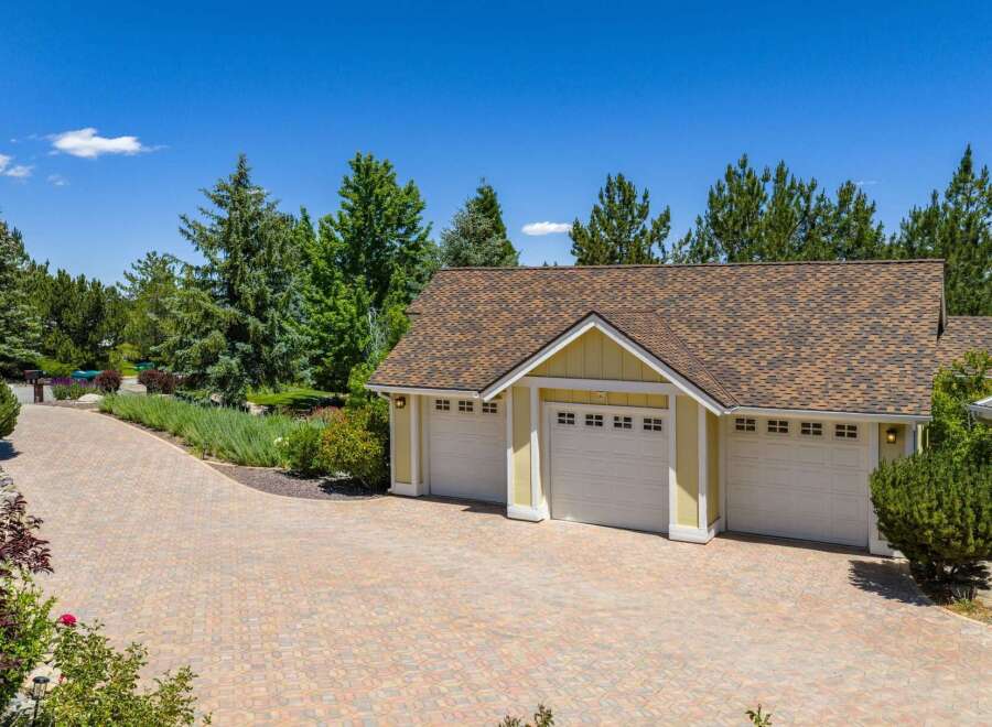 This property boasts a spacious three-car garage with charming yellow siding and white trim, perfect for vehicle storage and hobbies.