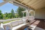Enjoy the outdoors from this covered patio, complete with comfortable seating and a beautiful view of the surrounding greenery.