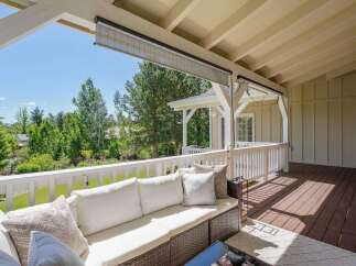 Enjoy the outdoors from this covered patio, complete with comfortable seating and a beautiful view of the surrounding greenery.