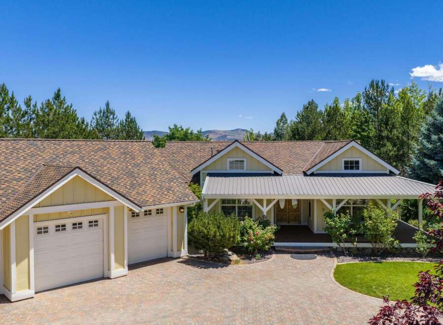 This charming yellow home features a welcoming covered front porch with white trim and a metal roof, perfect for enjoying the outdoors.