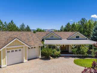 This charming yellow home features a welcoming covered front porch with white trim and a metal roof, perfect for enjoying the outdoors.