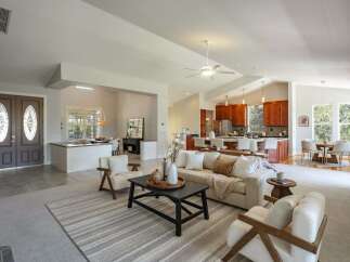Step into this beautifully appointed open-concept living space, featuring a modern kitchen with rich wood cabinetry and a spacious island perfect for entertaining.