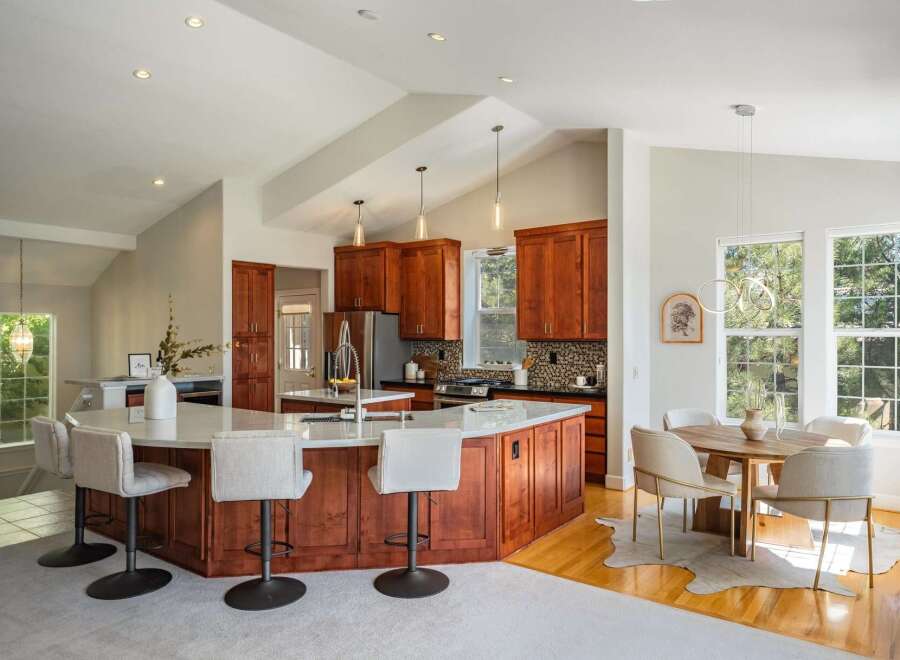 Experience the epitome of modern living in this stunning kitchen and dining area, featuring rich cherry wood cabinetry and a spacious island perfect for entertaining.