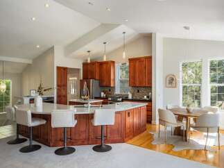 Experience the epitome of modern living in this stunning kitchen and dining area, featuring rich cherry wood cabinetry and a spacious island perfect for entertaining.