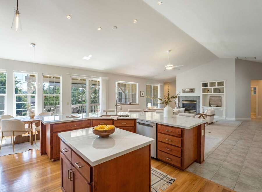 This spacious open-concept kitchen features a large island with marble countertops and ample wooden cabinetry, perfect for meal preparation and casual dining.