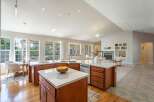 This spacious open-concept kitchen features a large island with marble countertops and ample wooden cabinetry, perfect for meal preparation and casual dining.