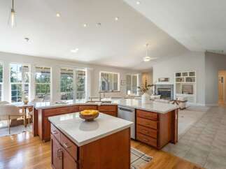 This spacious open-concept kitchen features a large island with marble countertops and ample wooden cabinetry, perfect for meal preparation and casual dining.