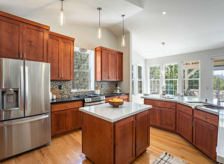 Experience luxury living in this stunning kitchen featuring rich cherry wood cabinetry and sleek granite countertops.