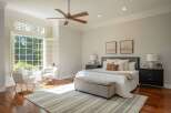Experience ultimate comfort in this serene bedroom, bathed in natural light from a large bay window with plantation shutters.
