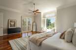 Experience luxurious living in this spacious master bedroom, featuring elegant plantation shutters that open to a serene outdoor view.