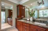This luxurious bathroom features a spacious double vanity with rich cherry wood cabinetry and granite countertops.