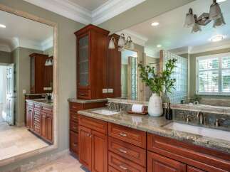 This luxurious bathroom features a spacious double vanity with rich cherry wood cabinetry and granite countertops.