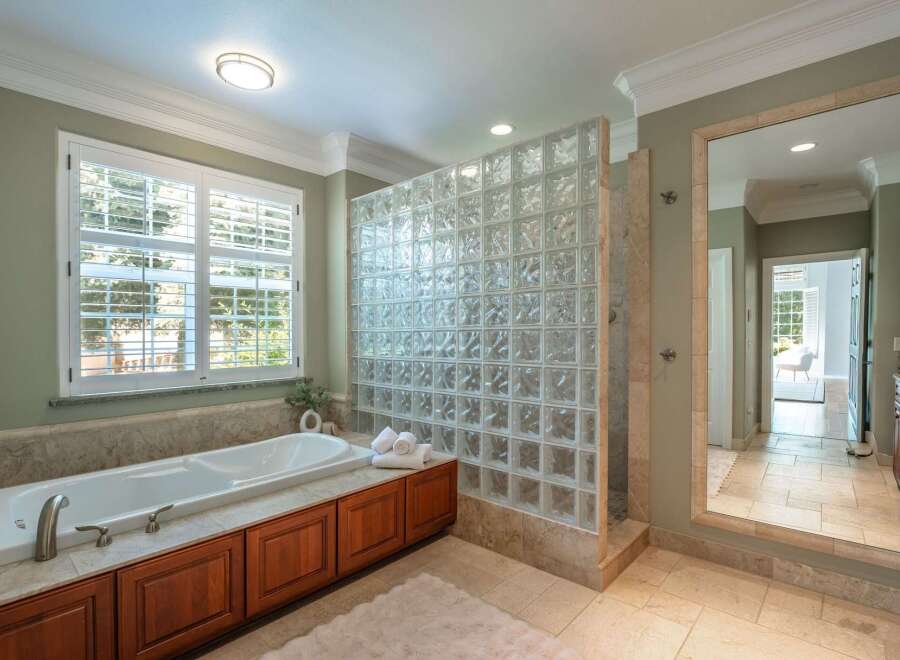 Indulge in luxury with this stunning bathroom featuring a deep soaking tub and a modern glass block shower enclosure.