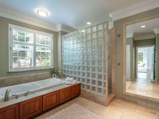 Indulge in luxury with this stunning bathroom featuring a deep soaking tub and a modern glass block shower enclosure.