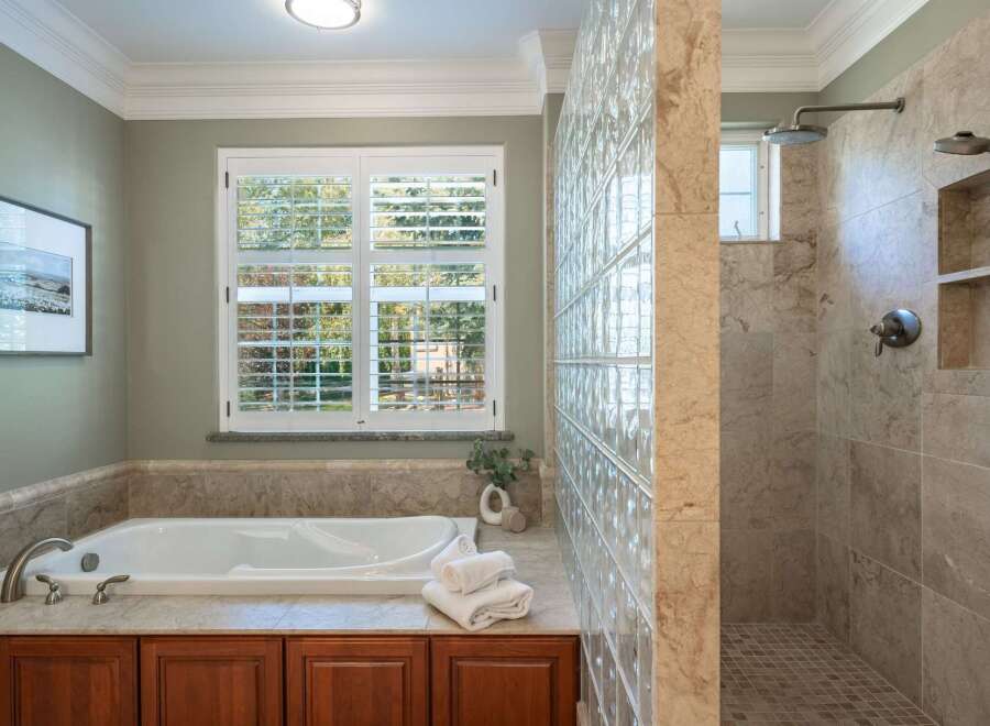 Indulge in luxury with this stunning bathroom featuring a deep soaking tub and a spacious walk-in shower with dual showerheads.